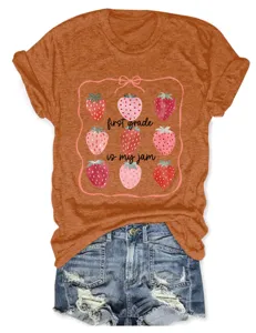 Gros plan sur le t-shirt en coton orange chiné avec un joli imprimé fraise et lettres.