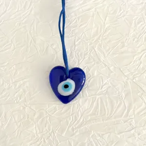 Gedetailleerde close-up van blauw boze oog hart glas hanger, traditioneel Turks amulet.