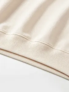 Kids sweatshirt fabric detail showing soft beige cotton texture and ribbed hem design.