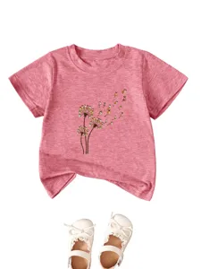 Λεπτομέρεια ροζ βρεφικό T-shirt με χαριτωμένο σχέδιο κουτάβια πικραλίδα και λευκά παπούτσια.