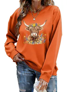 Close-up detail of the orange sweatshirt featuring a charming floral Highland cow graphic.