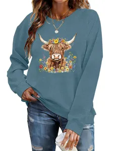 Close-up detail of the blue sweatshirt featuring a charming highland cow and colorful flower print.