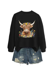 Details view of casual women black sweatshirt with highland cow graphic and denim shorts.