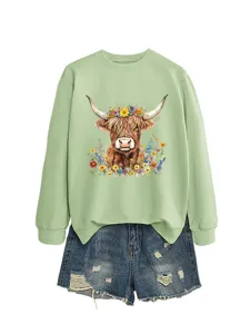 Light green crewneck sweatshirt featuring highland cow floral graphic paired with denim shorts.