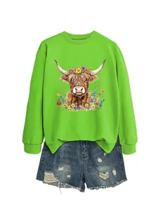 Green long sleeve sweatshirt with floral highland cow graphic paired with denim shorts.