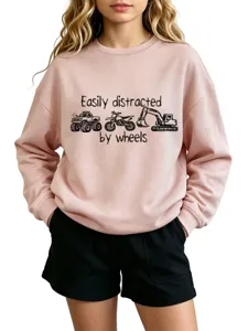 Nahaufnahme des rosa Pullovers mit Rundhalsausschnitt, lustigem Fahrzeugdruck und Schriftzug.