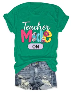 Casual green short-sleeve t-shirt for women with teacher mode graphic and denim shorts styling.