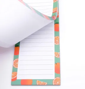 Primer plano detallado del bloc de notas magnético con diseño de naranja y páginas con líneas.