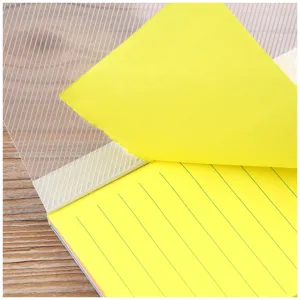 Detailed close-up shot of yellow lined sticky note with clear protective cover on wood texture.