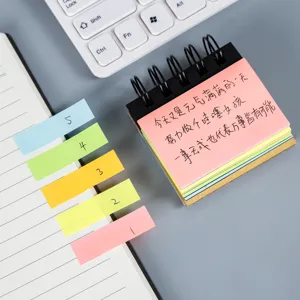 Primer plano de notas adhesivas en espiral y pestañas de índice coloridas en escritorio.