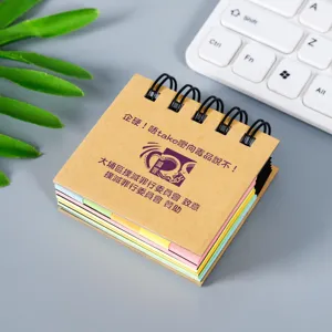 Bloc de notas de espiral compacto con notas adhesivas de colores en escritorio gris de cerca