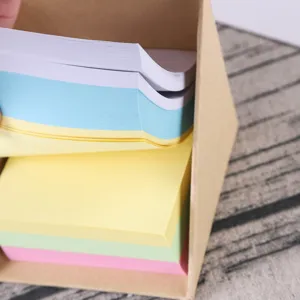 Close-up detail view of colorful square sticky memo pads placed in a kraft paper dispenser box.