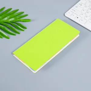 Lime green minimalist memo notebook detail view, colorful sticky index tabs on grey desk surface.