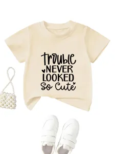Vista dettagliata della maglietta beige per bambini a maniche corte con testo carino e accessori.