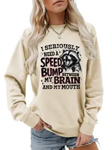 Waschbär Grafik Sweatshirt Detail mit humorvollem Spruch auf weichem beigen Stoff.