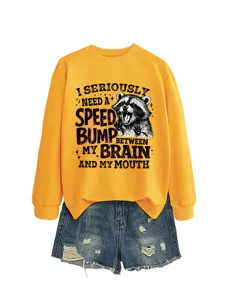Detailansicht des lustigen Waschbär-Grafikdrucks auf dem lässigen gelben Pullover.