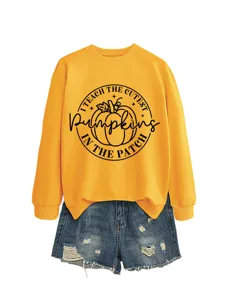 Detailansicht des stilvollen gelben Sweatshirts mit niedlichem Kürbisgrafik und Jeansshorts.