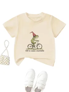 Détail de t-shirt graphique beige montrant l'imprimé mignon de grenouille à vélo et coton.