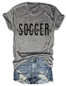 Gros plan détaillé du t-shirt gris à imprimé graphique soccer mom associé à un short en denim.
