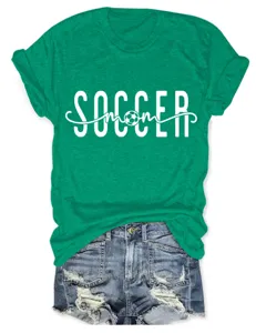 Détail de t-shirt green soccer mom avec impression graphique blanche et manches courtes.