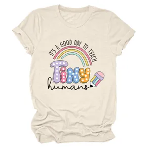 Gros plan détaillé du t-shirt graphique beige avec citation de professeur et joli arc-en-ciel.