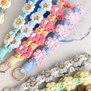 Detail view of handmade woven daisy flower phone lanyard strap and keychain with metal ring.
