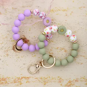 Detail view of sweet silicone beaded wristlet keychains with floral charms and gold hardware.