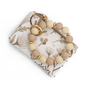 Gros plan sur le porte-cartes en cuir floral et le porte-clés bracelet en perles silicone.