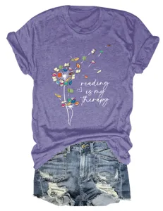 Women's casual purple short sleeve t-shirt featuring a cute reading book dandelion graphic design.