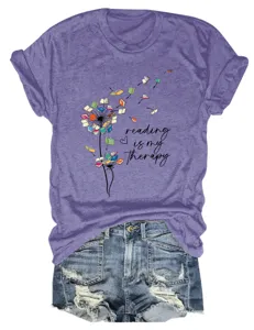 Purple short sleeve t-shirt featuring a creative reading book dandelion graphic detail view.