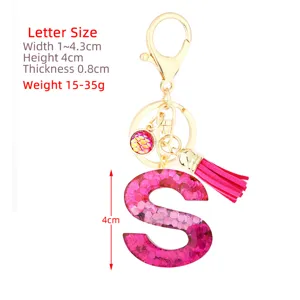 Pink glitter letter resin keychain with gold clasp, fish scale charm and tassel pendant.
