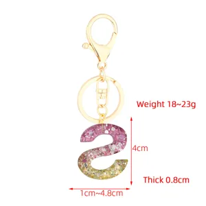 Resin glitter letter keychain detail view showcasing the sparkling pink 'S' charm and gold hardware.