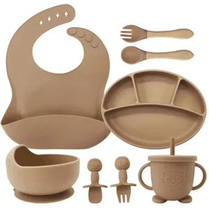 Silicone baby feeding set featuring sectioned plate, bowl, bib, spoon, fork, and cup.
