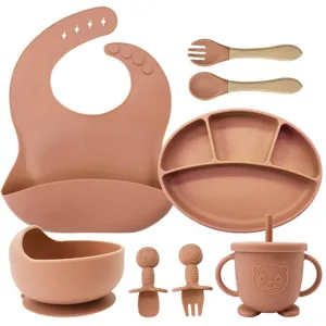 Silicone baby feeding set detail, suction plate, bowl, fork, spoon, cute bib design.