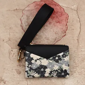 Women bifold floral print card holder wallet with black wrist strap and keychain. Detail view.