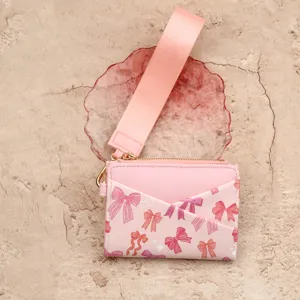Pink leather card holder featuring wrist strap and cute bow print for daily women use.
