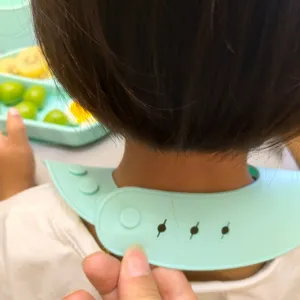 Silicone baby bib detail showing adjustable buttons, soft food grade material for infants.