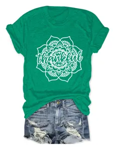 Green short sleeve t-shirt featuring a white floral mandala and thankful graphic print detail.