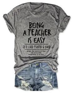 Primo piano dettaglio della t-shirt a maniche corte con slogan da insegnante grigia e jeans.