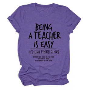 Dettaglio di t-shirt viola a maniche corte con stampa di citazione divertente da insegnante.