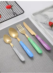Dettaglio set posate in acciaio inox con manico in marmo e finitura opaca color oro.