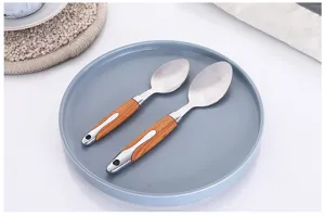 Detalle de cuchara de acero inoxidable con mango de grano de madera y acabado pulido fino.