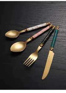 Detalle de cubiertos de acero inoxidable dorado con mango de mármol cuchara tenedor.