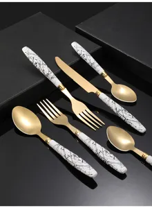 Detailed close-up of stainless steel cutlery set with gold finish and marble pattern.