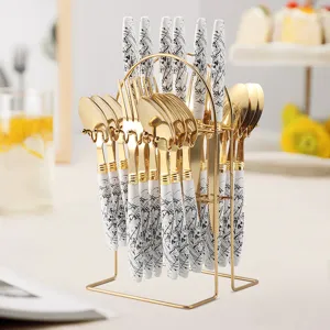 Stainless steel cutlery set with gold finish, black white ink splatter handles, storage rack