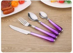 Detalle del juego de cubiertos de acero inoxidable con tenedor cuchara y cuchillo morados.
