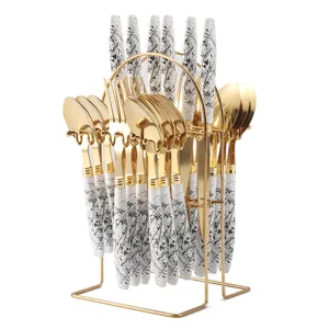 Gold stainless steel cutlery set with black and white ink pattern and storage rack.