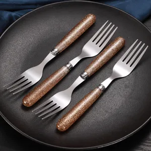 Set di quattro forchette in acciaio inossidabile con manici glitterati dorati per la cucina.