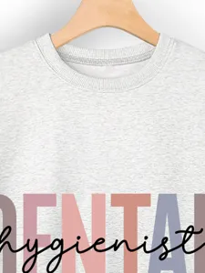 Nahaufnahme eines hellgrauen Langarm-Sweatshirts mit Rundhalsausschnitt und buntem Textdruck.