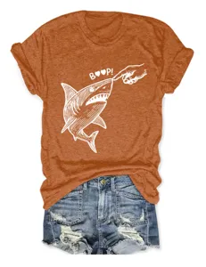 Nahaufnahme des lustigen Haifisch Boop Grafik Details auf dem orangefarbenen T-Shirt.